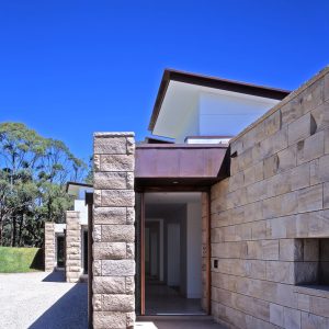 A stone house featuring a prominent stone wall and a rustic wooden door