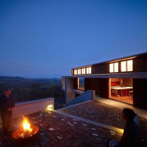 A man relaxes on a brick patio beside a fire pit